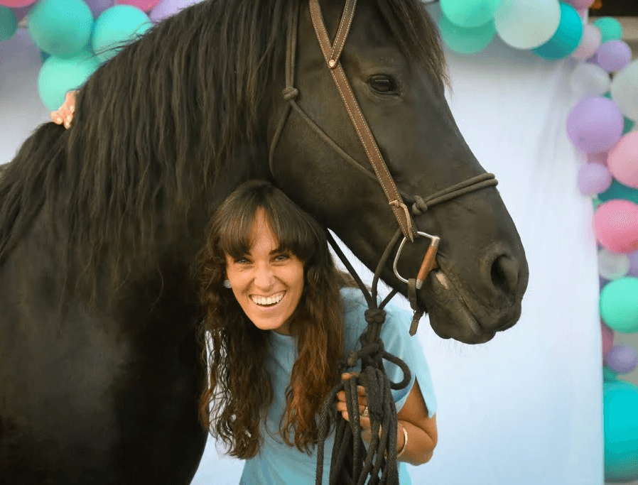 Hillary smiling beside a horse