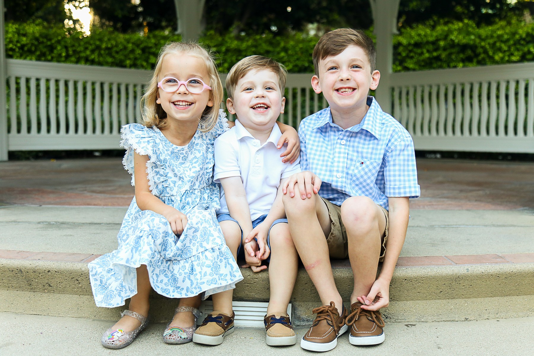 Three children smiling together during a family portrait session