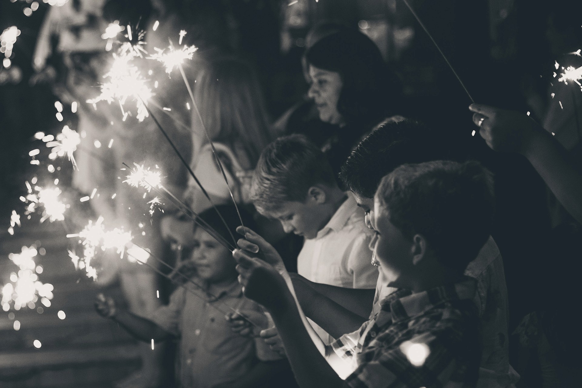 Children holding sparklers during an evening wedding celebration