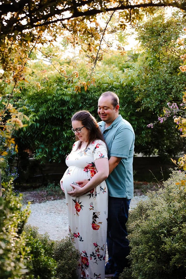 Maternity couple framed by greenery