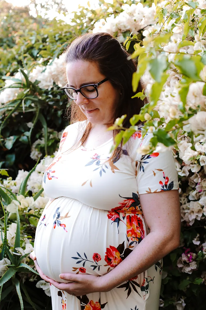 Maternity portrait by a wall of flowers